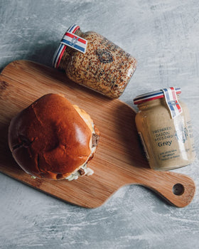 Grey Poupon Dijon mustard on a dining table setup ready to elevate meals.