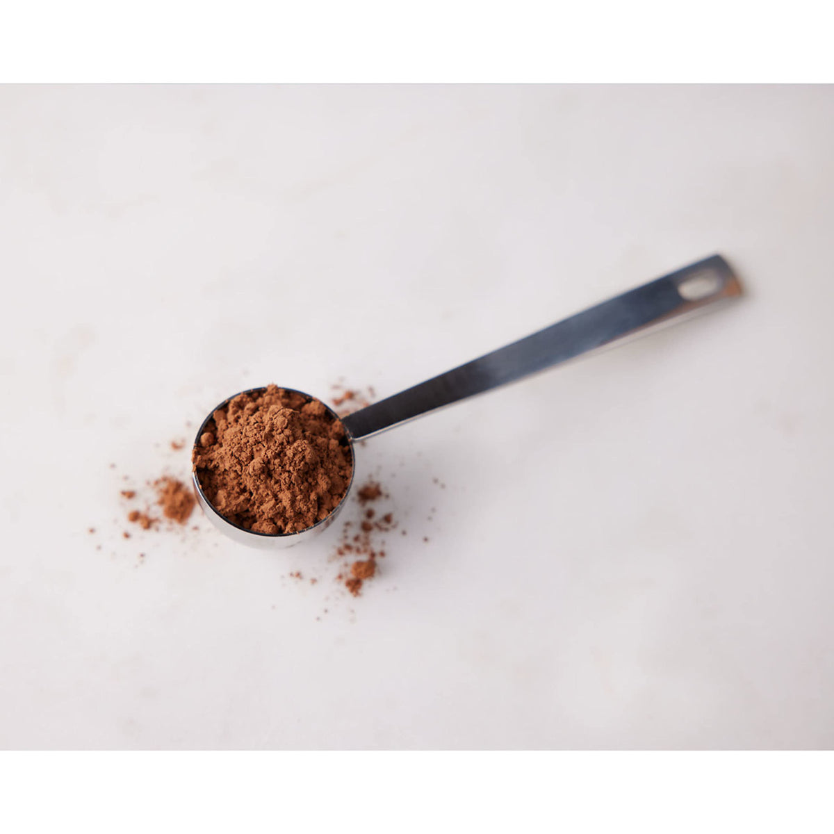 HERSHEY'S unsweetened cocoa powder measuring into batter for brownies