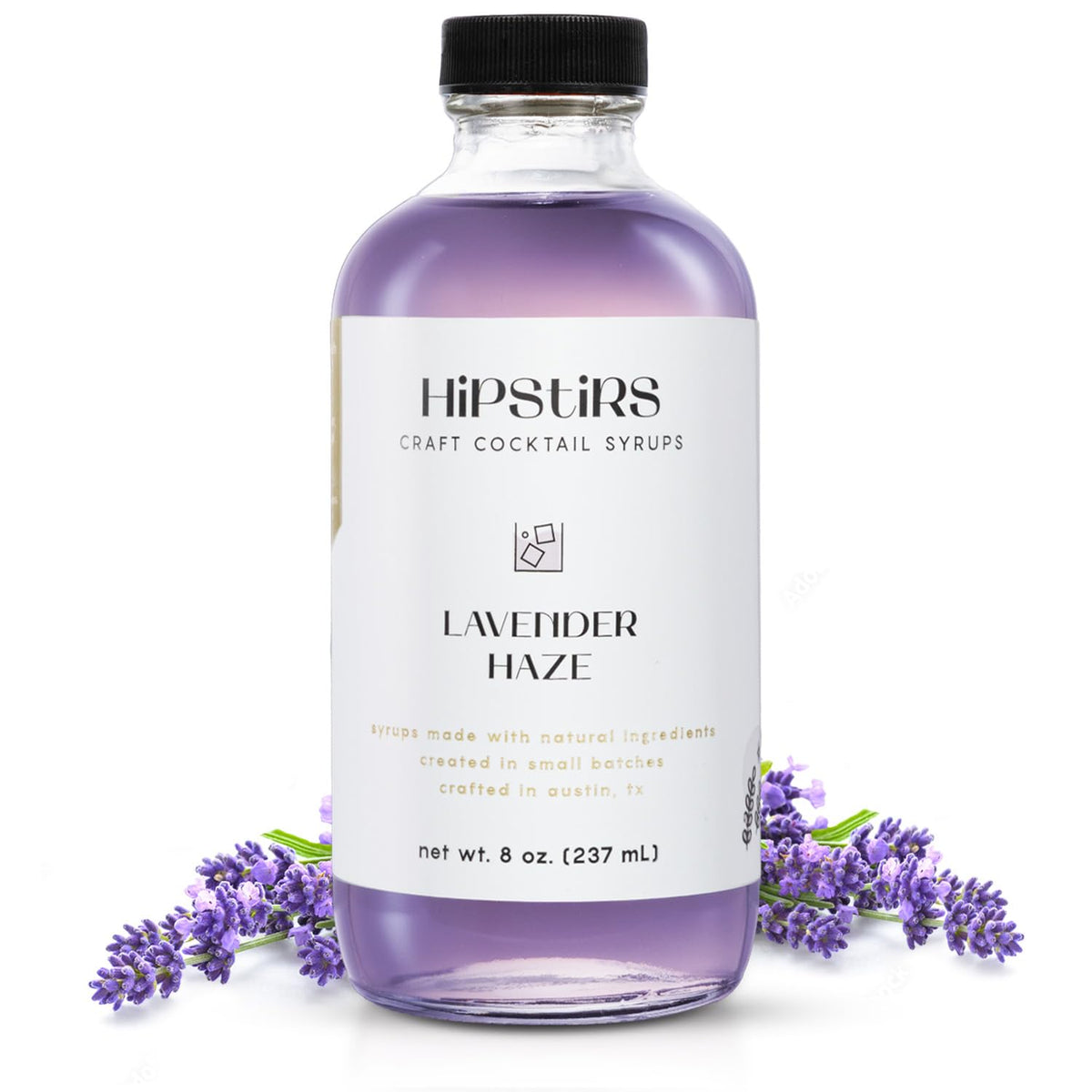 HipStirs Lavender Haze Syrup bottle on wood highlights premium ingredients for craft cocktails.