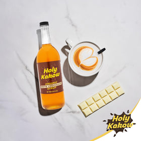 Holy Kakow White Chocolate Syrup on kitchen counter enhances drinks and desserts.