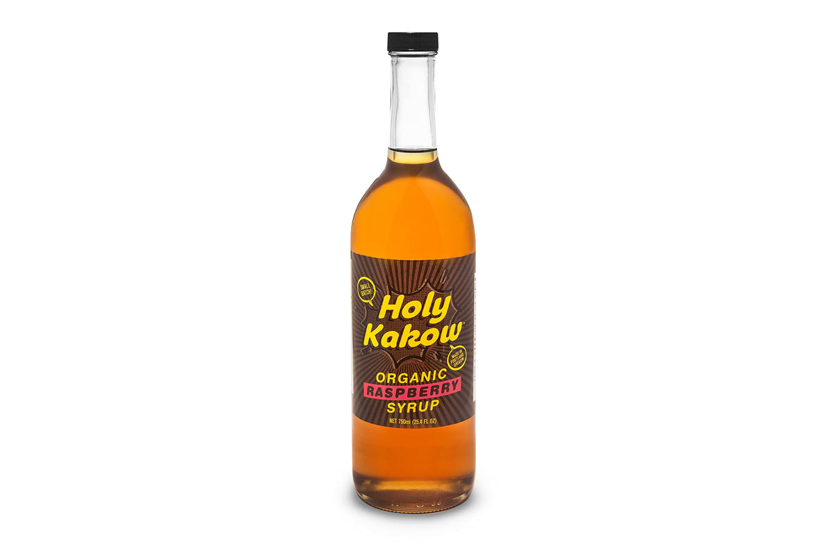 Holy Kakow Raspberry Syrup bottle beside a latte for a flavorful coffee boost.
