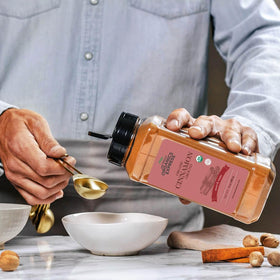 HQOExpress cinnamon powder being scooped, ideal for coffee and oats.