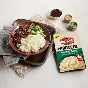 Idahoan Roasted Garlic +Protein served on plate with creamy mashed potatoes.