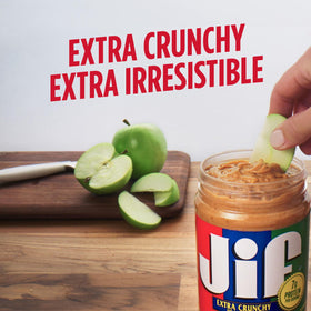 Spoon dipping into Jif Crunchy Peanut Butter reveals visible peanut bits and aroma.
