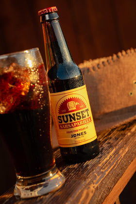 Jones Soda Fallout Sunset Sarsaparilla bottle at casual gathering.