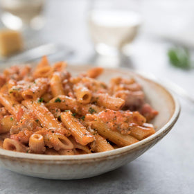 Jovial brown rice pasta cooking in boiling water with steam rising.