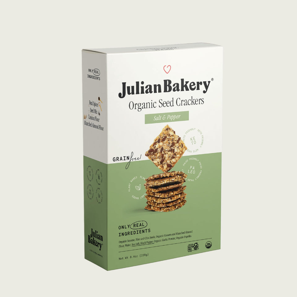 Julian Bakery Paleo Thin Crackers Salt Pepper on wooden board, gluten-free crunch for snacking.