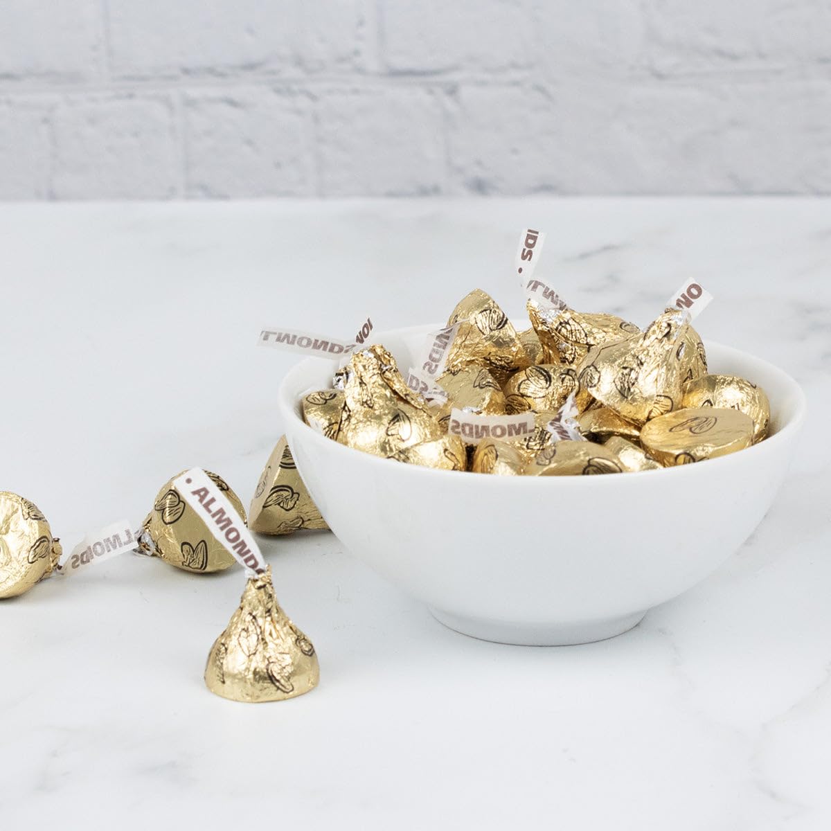 Just Candy gold almond-filled kisses displayed on a wedding candy bar.