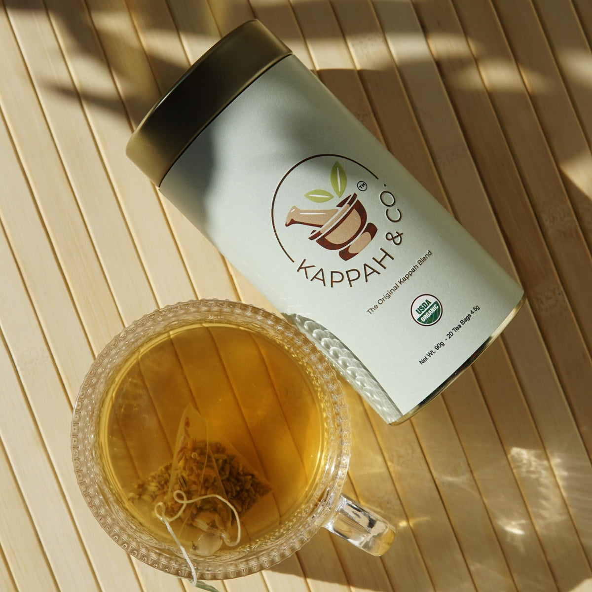 Kappah fennel tea bag steeping beside a clear cup and warm glow.