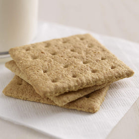 Kellogg's Grahams crackers dipping with peanut butter for a tasty bite.