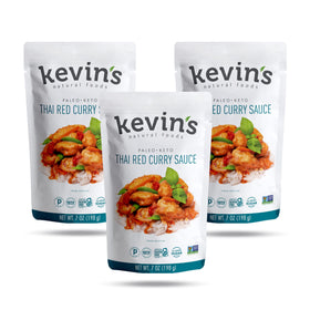 Kevin's Natural Foods Thai Red Curry Sauce bottle on stove, elevating quick gluten-free meals.