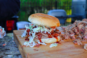 Grill scene with Killer Hogs sauce and sizzling meat.