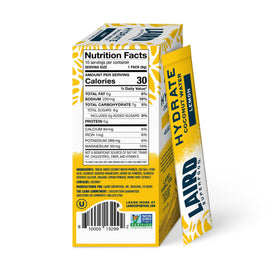 Pouring a Laird Superfood Hydrate Lemon stick into water for refreshing electrolytes.