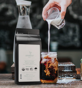 Lifeboost Half Caff cup with steam emphasizing rich aroma and low acidity profile.
