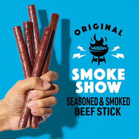 Lorissa's Kitchen Smoke Show beef stick in hand; ideal for quick protein during workouts.