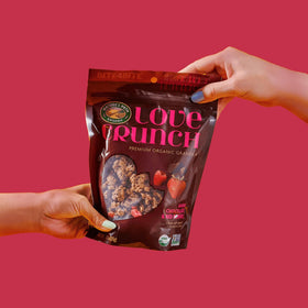 Love Crunch granola being poured into a yogurt bowl for topping.