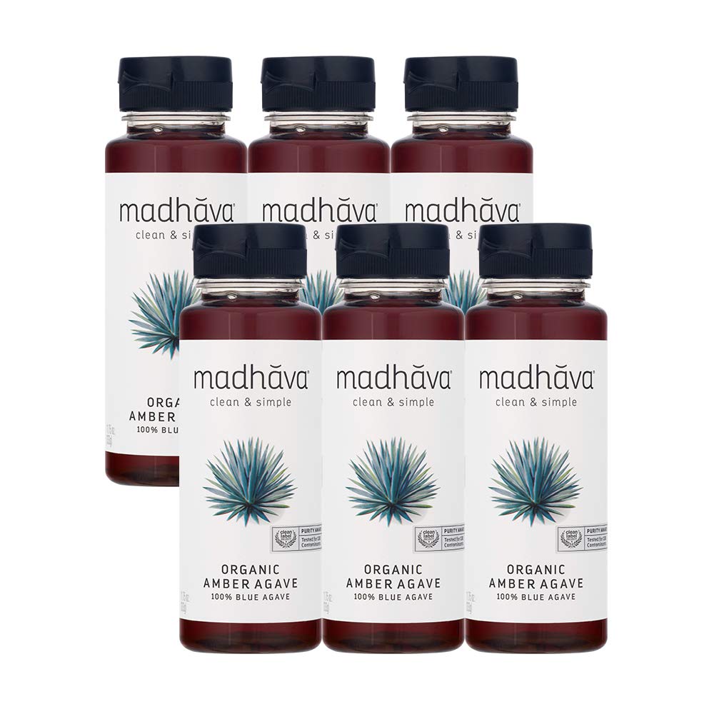 Madhava Blue Agave bottle beside a steaming mug of coffee.