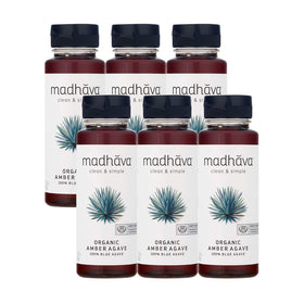 Madhava Blue Agave bottle beside a steaming mug of coffee.