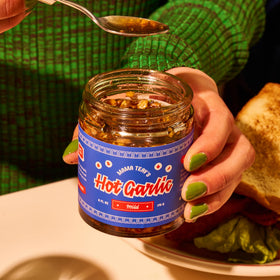 Mama Teav's Mild Garlic Chili Crisp pour demonstrates savory umami for noodles and rice.