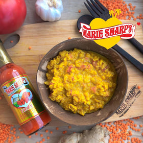 Glass bottle of Marie Sharp's Fiery Hot Habanero Sauce being poured.