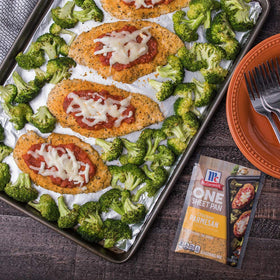 Raw chicken and broccoli on a pan seasoned with McCormick mix.