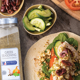 Greek seasoning ingredients arranged beside the jar in natural light.