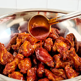 Chef preparing batch with gochujang seasoning for quick flavor in a busy kitchen.