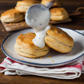 In a cooking bowl, whisking creates lump-free peppered gravy.