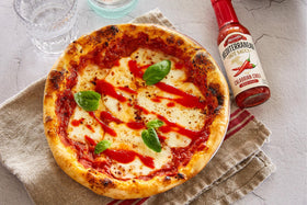 Mezzetta hot sauce sampler trio jars on white surface suggest premium assortment.