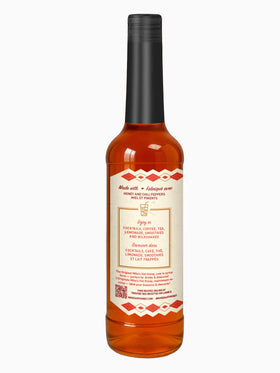 Mike's Hot Honey Original bottle next to a coffee cup, perfect for lattes and macchiatos.