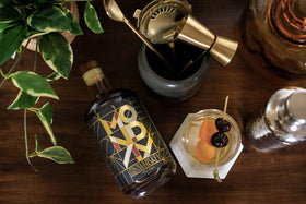 Friends toasting with MONDAY Zero Alcohol Whiskey cocktails at a casual gathering
