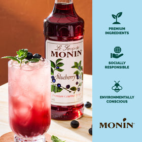 Monin Blueberry Syrup label beside a vibrant blueberry cocktail.