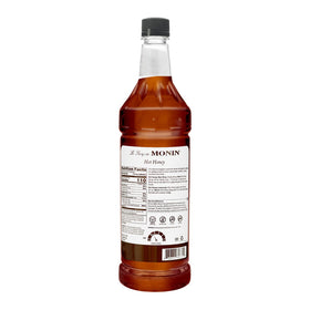 Pouring Monin Hot Honey Syrup into lemonade for a balanced sweet-spicy twist.