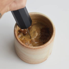 Pouring mudwtr coconut creamer powder from a scoop into a cup