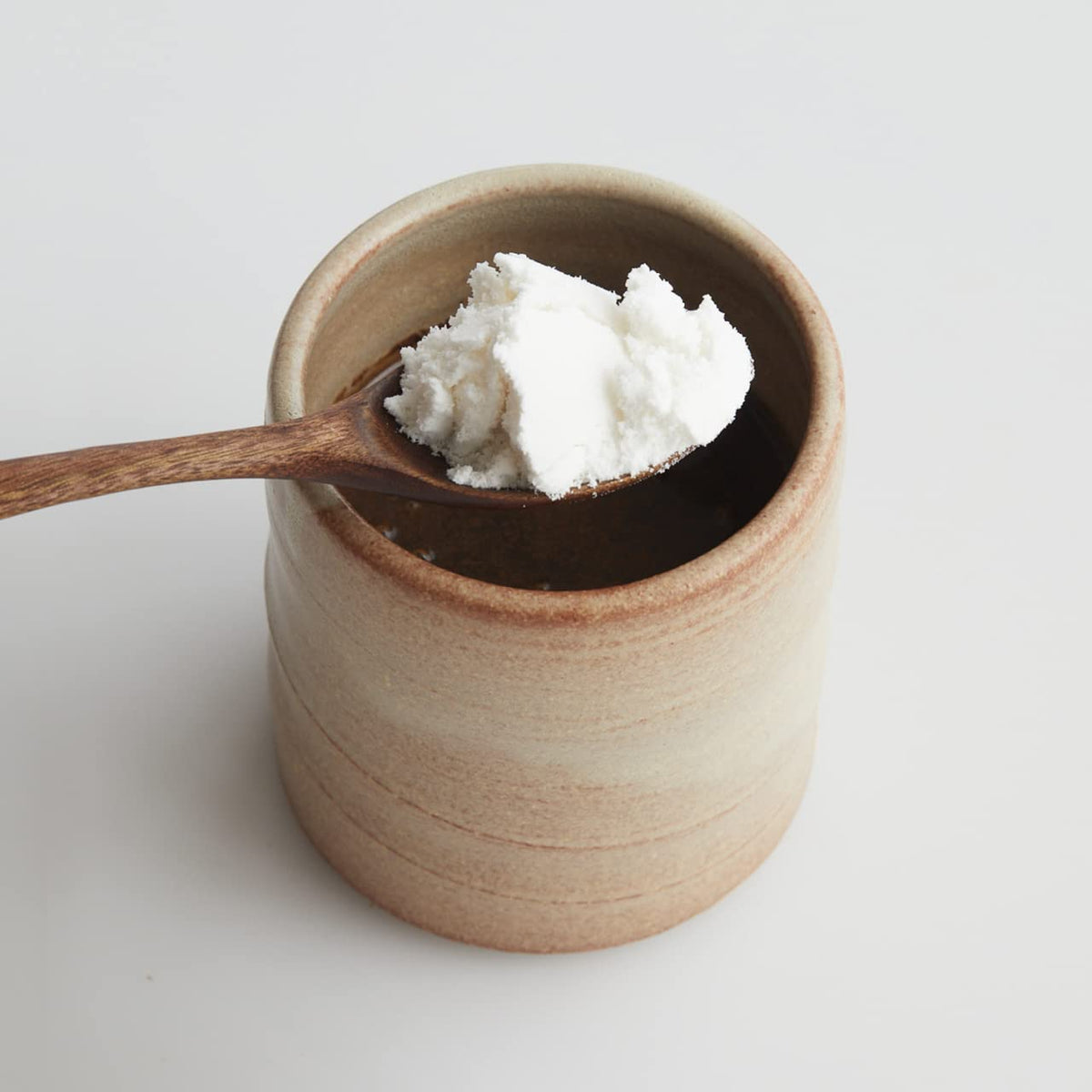 Stirring mudwtr coconut creamer into a cup for a silky dairy-free texture