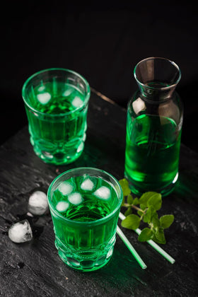 Stirring Waldmeister Syrup into sparkling water for a green lemonade.