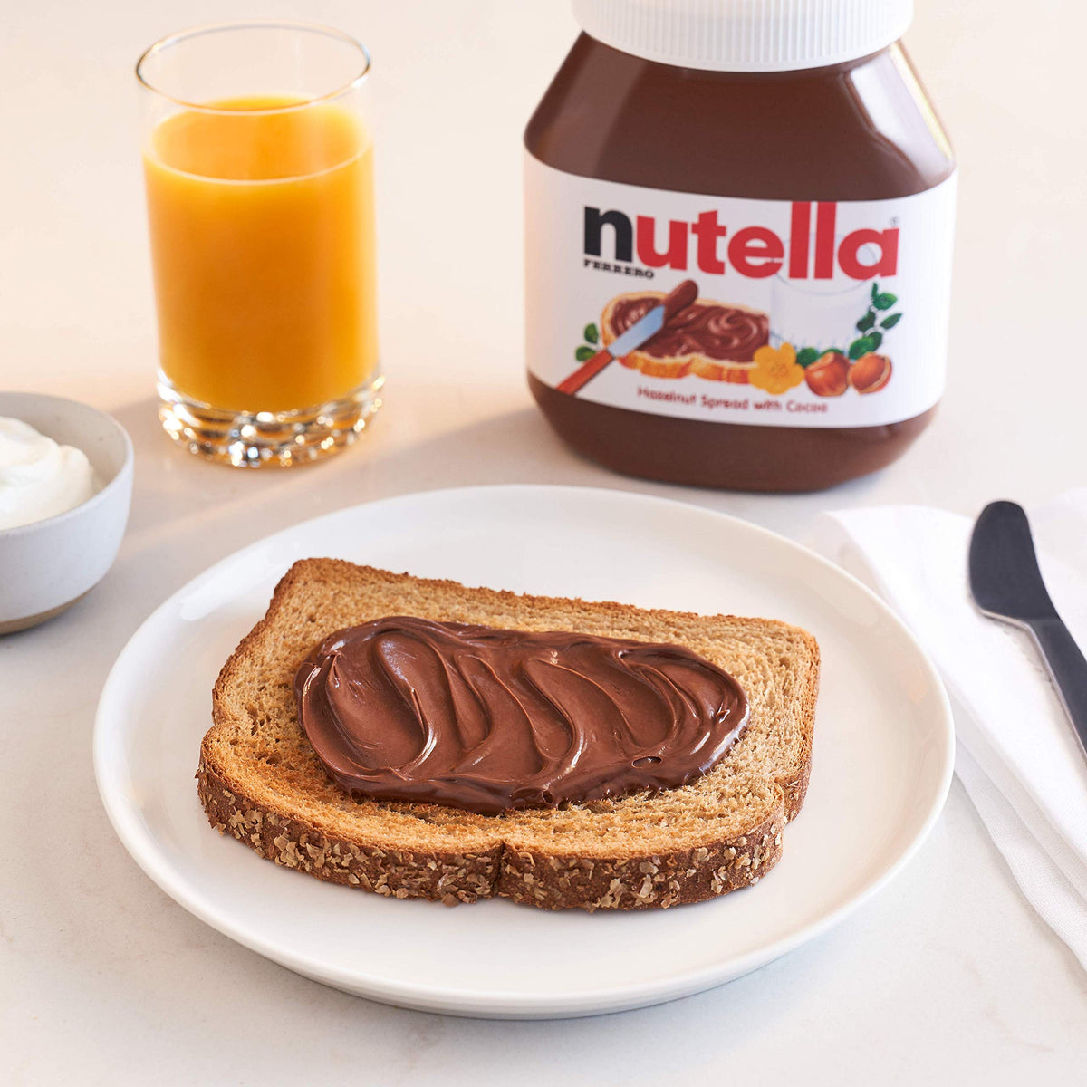 Nutella jar and spoon swirled into yogurt for a quick treat.