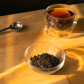Organic Positively Hojicha steeping in a glass teapot, releasing warm aroma.