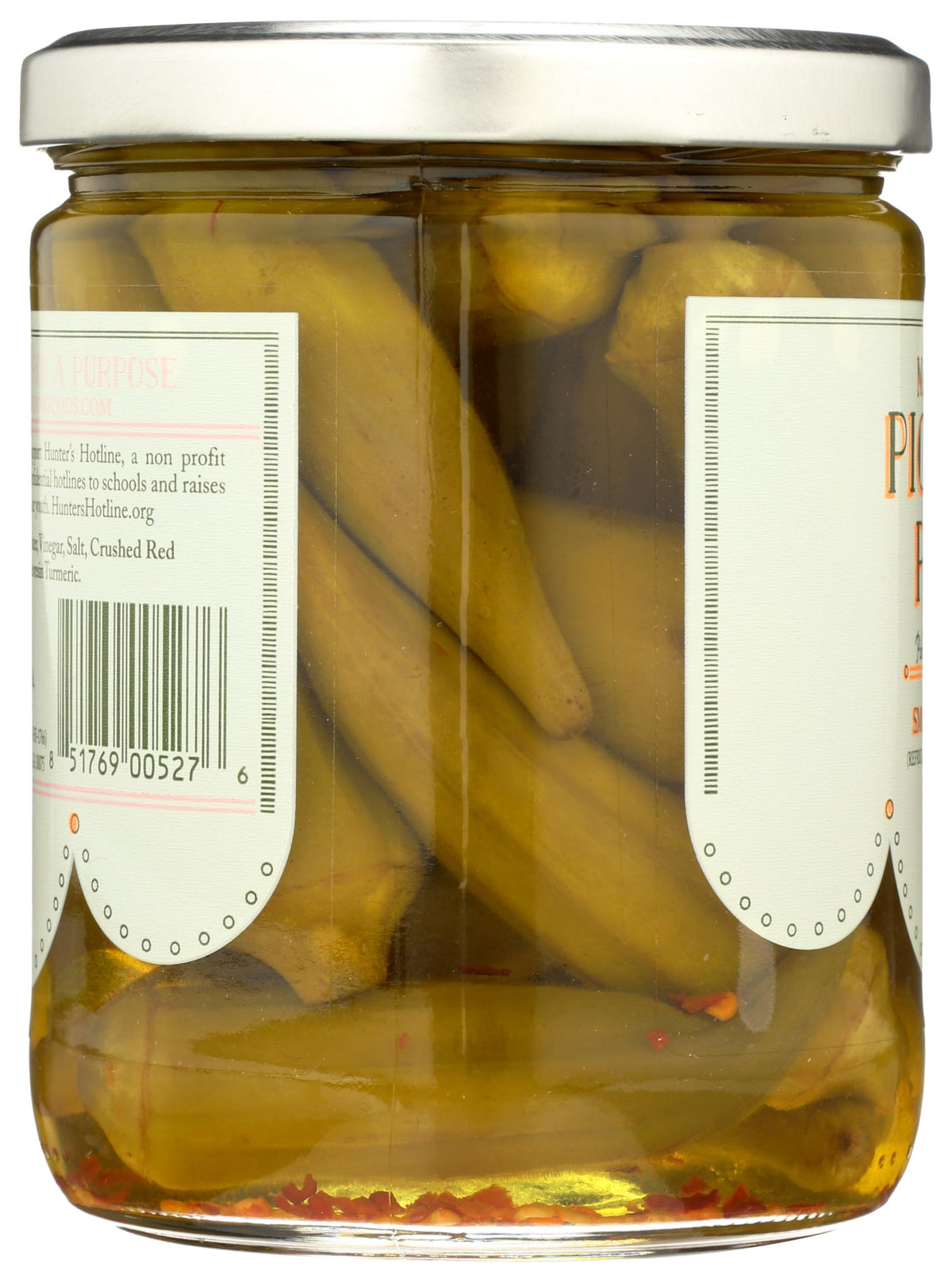 Okra pods behind glass jar showcase Pickled Pink briny aroma and vibrant texture.