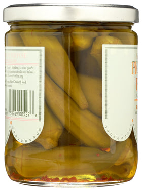 Okra pods behind glass jar showcase Pickled Pink briny aroma and vibrant texture.