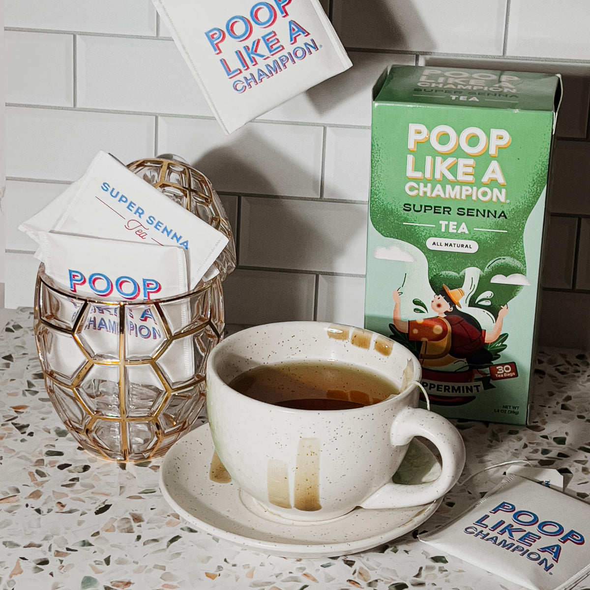 Kettle steaming beside a ready-to-brew Poop Like A Champion tea setup.