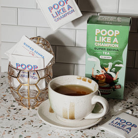 Kettle steaming beside a ready-to-brew Poop Like A Champion tea setup.