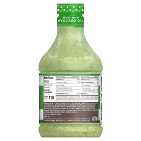 Close-up pouring Primal Kitchen Avocado Lime Dressing over a fresh salad