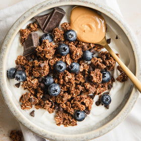 Purely Elizabeth granola in bowl with milk and berries