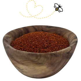 Raw Essentials New Mexico Red Chili Powder pouring from the jar into a spoon for depth and aroma.