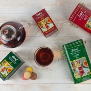 Sadaf Cardamom Tea tin on shelf with pastries, ideal pairing.