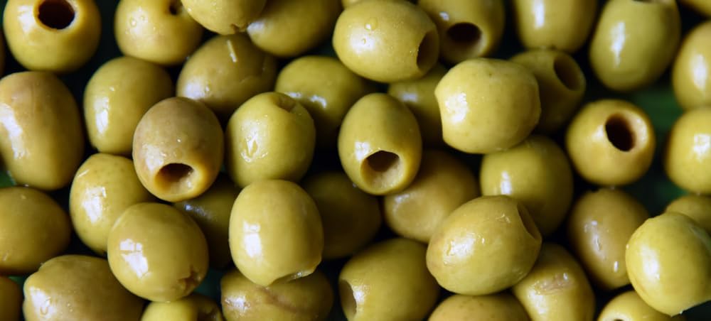 Castelvetrano olives on a charcuterie board with a vibrant green color.