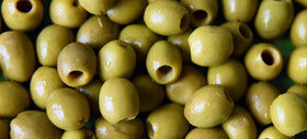 Castelvetrano olives on a charcuterie board with a vibrant green color.