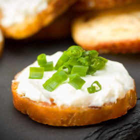 Schwartz Brothers Garlic and Herb Bagel Chips with dip on a cheese board.