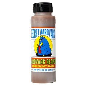 Secret Aardvark Reaper Hot Sauce bottle being poured, adding smoky spice to dishes.